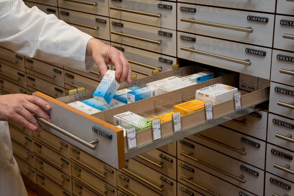 Apotheker taking medication from cabinet in a pharmacy