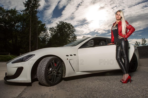 Young woman with long blond hair poses with white Maserati Gran Turismo MC Stradale