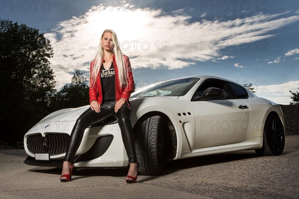 Young woman with long blond hair poses with white Maserati Gran Turismo MC Stradale