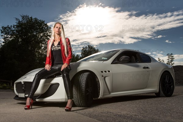 Young woman with long blond hair poses with white Maserati Gran Turismo MC Stradale