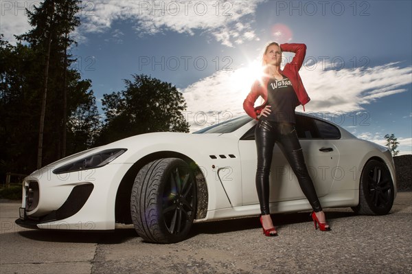 Young woman with long blond hair poses with white Maserati Gran Turismo MC Stradale