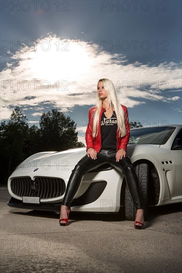 Young woman with long blond hair poses with white Maserati Gran Turismo MC Stradale