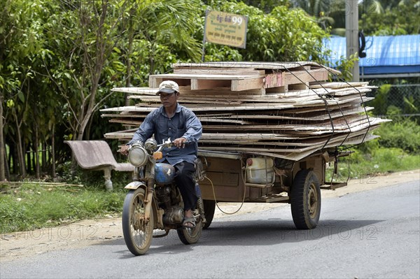 Man with moped and trailer transporting large wooden panels