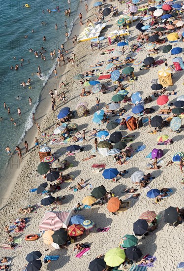 Many people with colorful sunshades at Tropea Beach