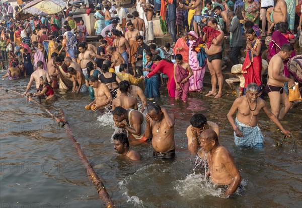 Hindu believers bath and perform ritual bath and puja prayers at ghats in the River Ganges