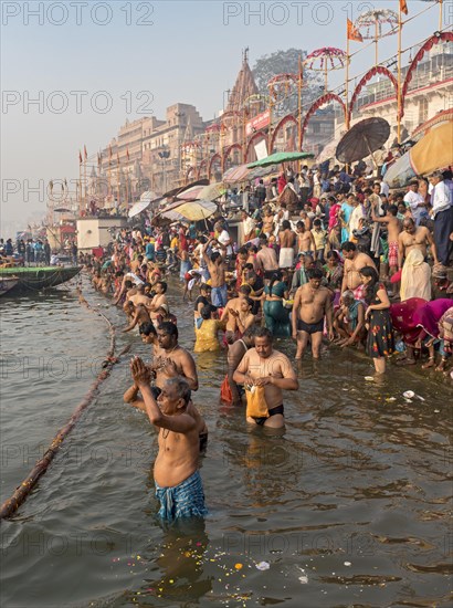 Hindu believers bath and perform ritual bath and puja prayers at ghats in the River Ganges