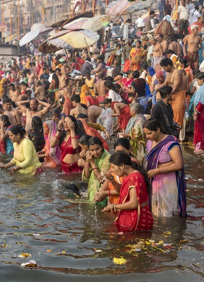 Hindu believers bath and perform ritual bath and puja prayers at ghats in the River Ganges