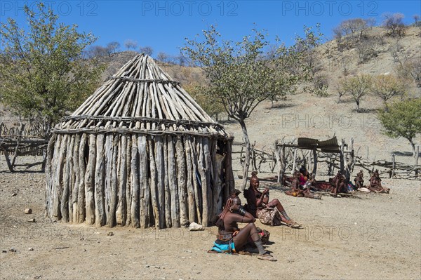 Himba women in a village with wooden huts