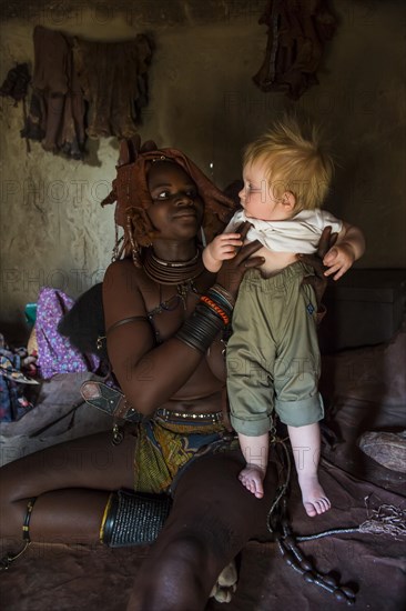 Himba woman holding a white tourist baby