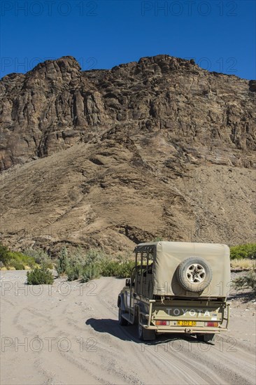 Tourist jeep driving through the deep sand searching for safari