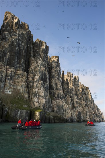 Tourists in zodiacs at cliffs of Alkefjellet