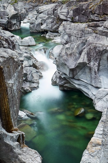 Green clear water in the rocky riverbed of gneiss rock