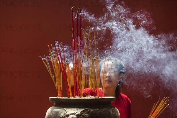 Young woman with burning incense sticks on Chinese New Year
