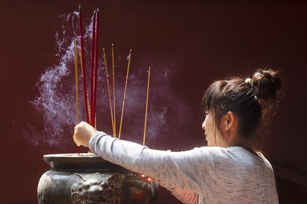 Young woman with burning incense sticks on Chinese New Year