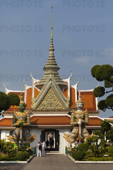 Tourists in front of the huge guard statues of the ordination hall of Wat Arun