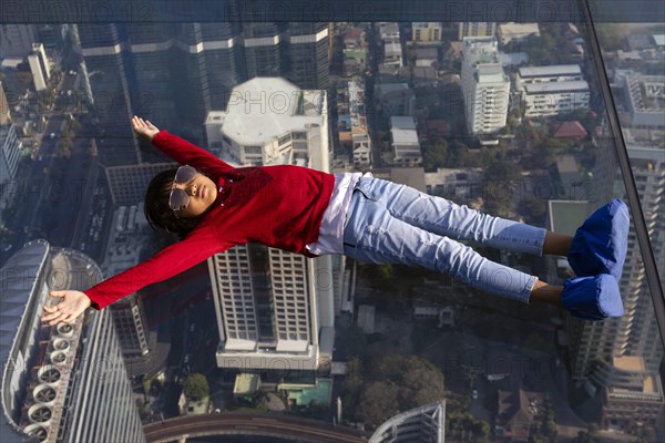 Little girl lies on the glass skywalk