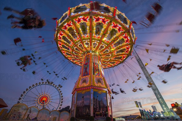 Rotating chain carousel and ferris wheel at the blue hour