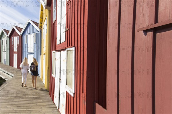 Two women walking next to fishing huts