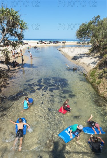 Children surfing on a board in river Eli Creek