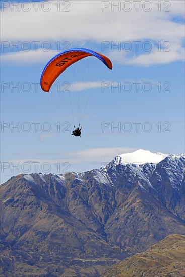 Paragliding over mountain range The Remarkables