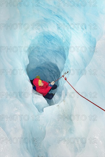 Rock climber moving up ice cave