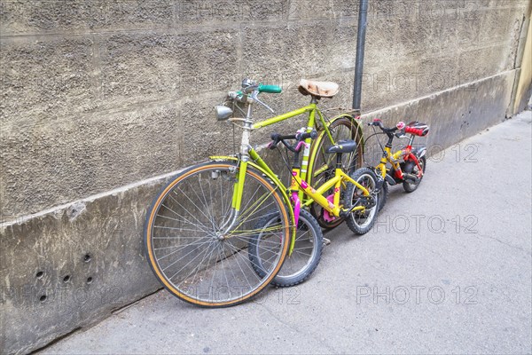 Bicycles for adult and children parked against wall