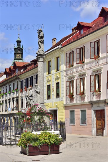 Nepomuk fountain in front of house facades on market square Mestni Trg with tower St. James' Church