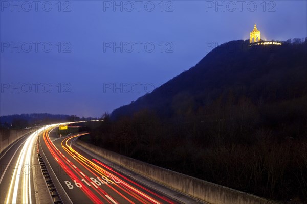 Illuminated Kaiser Wilhelm Monument over federal road with light traces of traffic