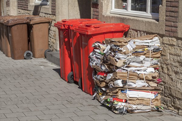 Red bins for waste glass and stacks of waste paper