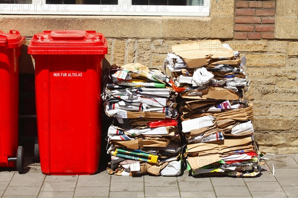 Red bins for waste glass and stacks of waste paper