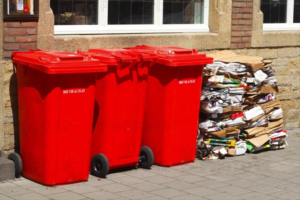 Red bins for waste glass and stacks of waste paper