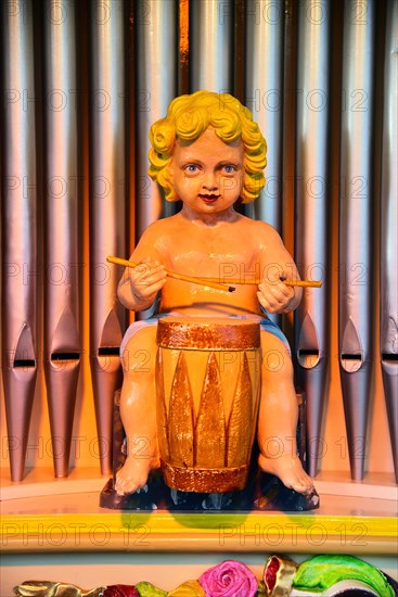 Drummer figure in front of organ pipes