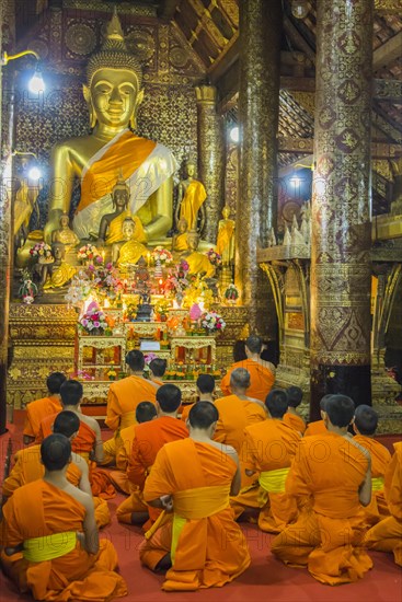 Buddhist monks praying in the temple Wat Xieng Thong