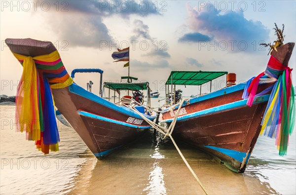 Moored colorful traditional long-tail boats on sandy beach