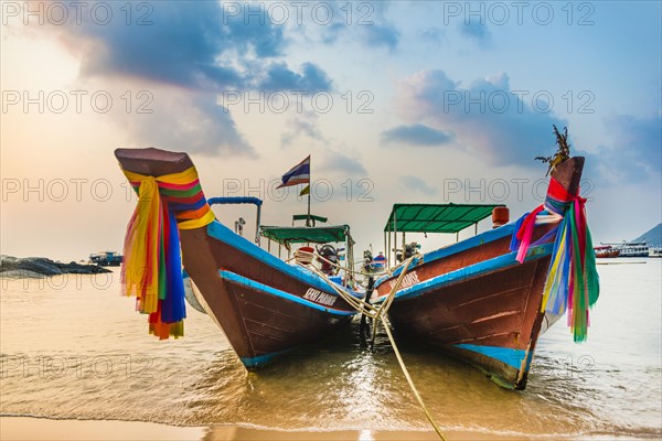 Moored colorful traditional long-tail boats on sandy beach