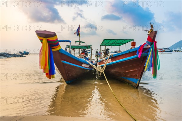 Moored colorful traditional long-tail boats on sandy beach