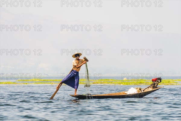 Local fishermen leg rowing on wooden boat
