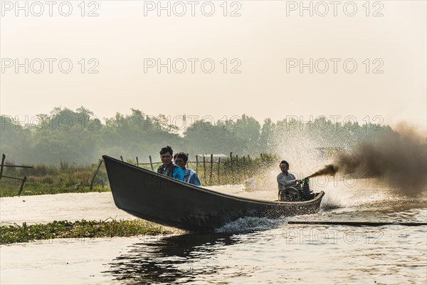 Locals on wooden motor boat with dark smoke