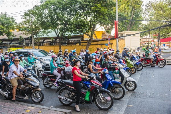 Crowd of scooter riders waiting at traffic light