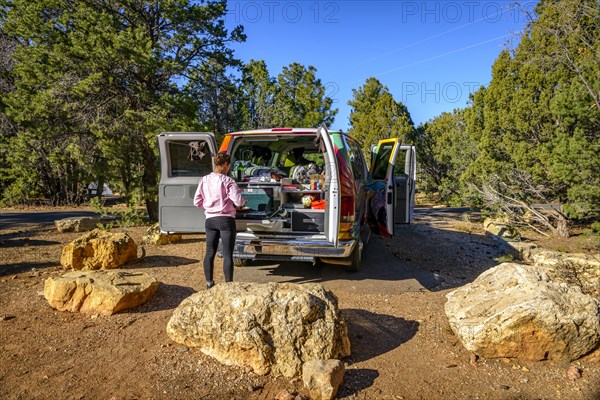 Young woman cooking at the gas stove of a camping van