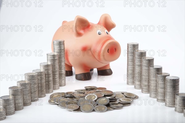 Piggy bank behind heaped and stacked coins