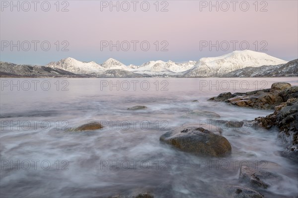 Coast in evening light and snow covered mountains