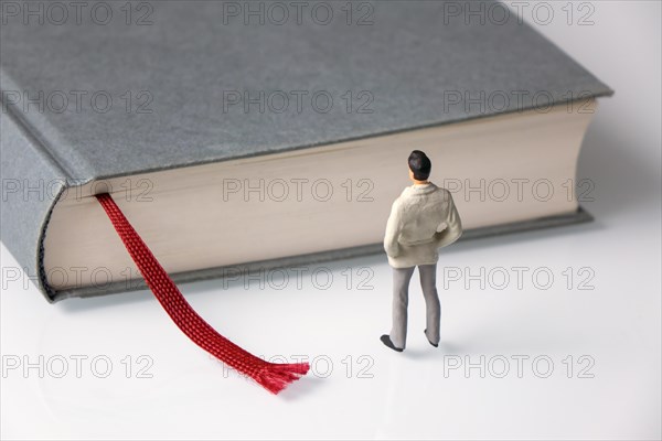 Male figure stands in front of grey book