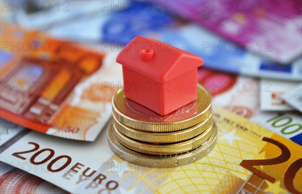 Cottage on pile with money coins and euro banknotes