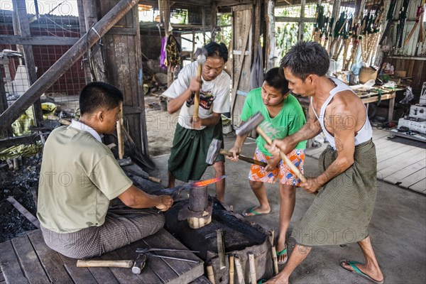 Local blacksmiths banging with hammers on glowing piece of metal