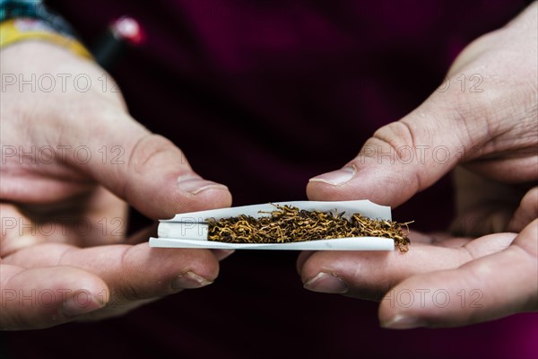 Hands rolling a cigarette with tobacco and filter