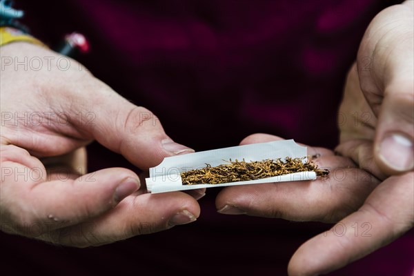 Hands rolling a cigarette with tobacco and filter