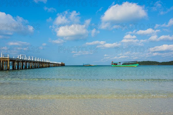 Pier on beach with boats in turquoise water at Saracen Bay on Koh Rong Sanloem island