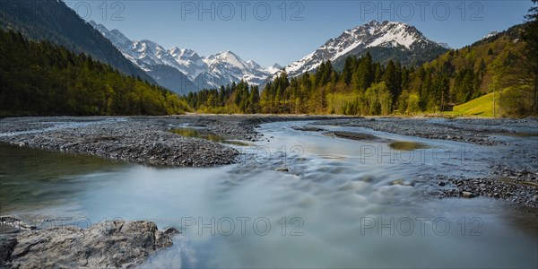 Stillach mountain stream in front of snow-covered mountain range