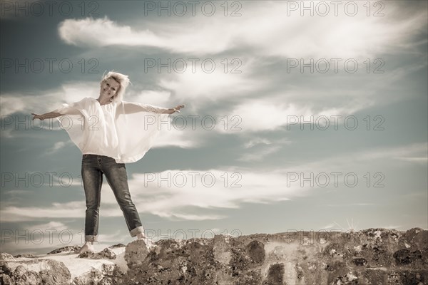 Woman standing on wall with arms outstretched